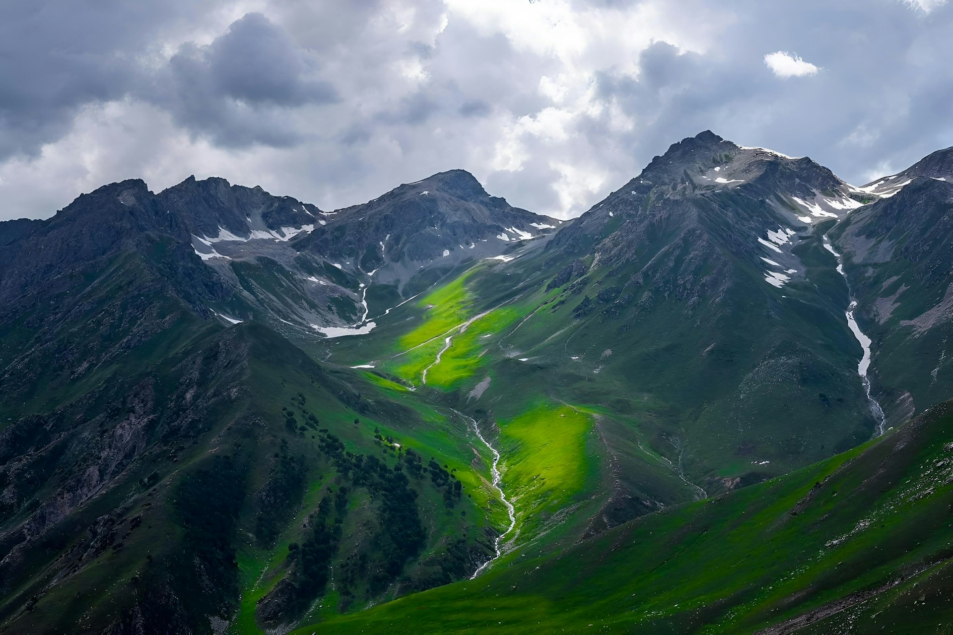 Mountain range above green grass in Kashmir